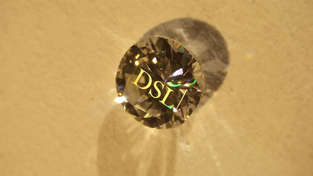 Round brilliant diamond with brand monogram "DSL" structured on the surface — Arteida femtosecond laser personalization for brands
